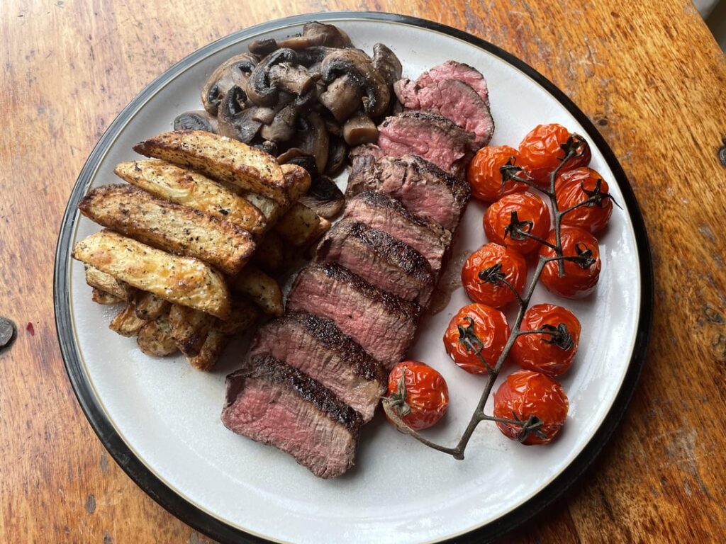 Fillet steak with homemade chips, fried mushrooms and roast tomatoes.