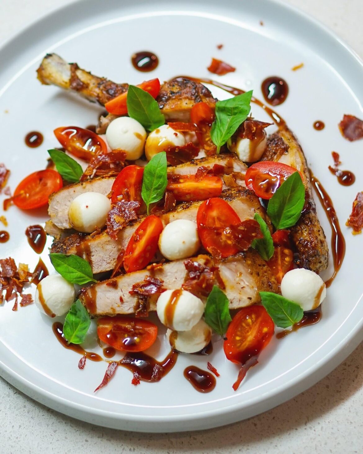 pork chop, grape tomatoes, bocconcini, balsamic glaze, prosciutto bits, and basil