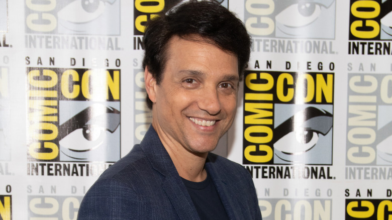 Ralph Macchio smiling in navy blazer and black shirt