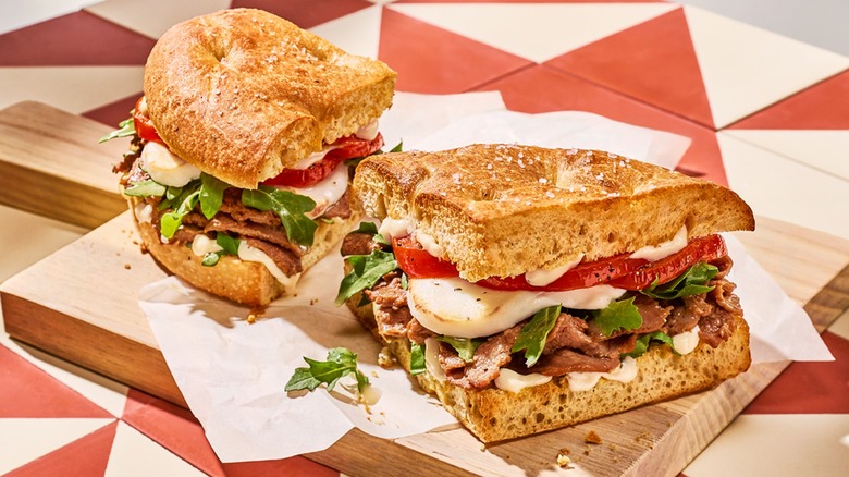 Panera's Italian Steak & Mozz sandwich cut in half on wood cutting board