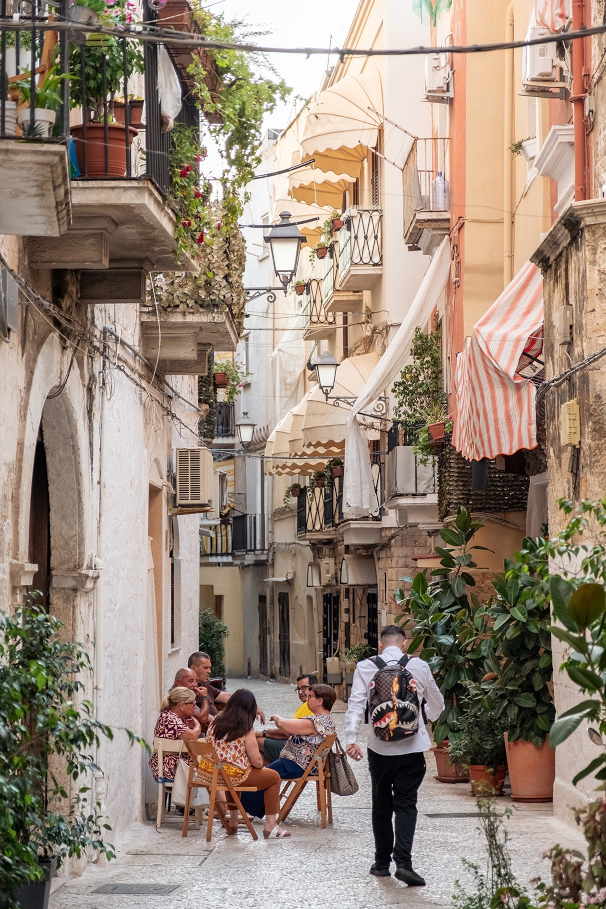 People sit in the narrow streets of an Italian town around a table