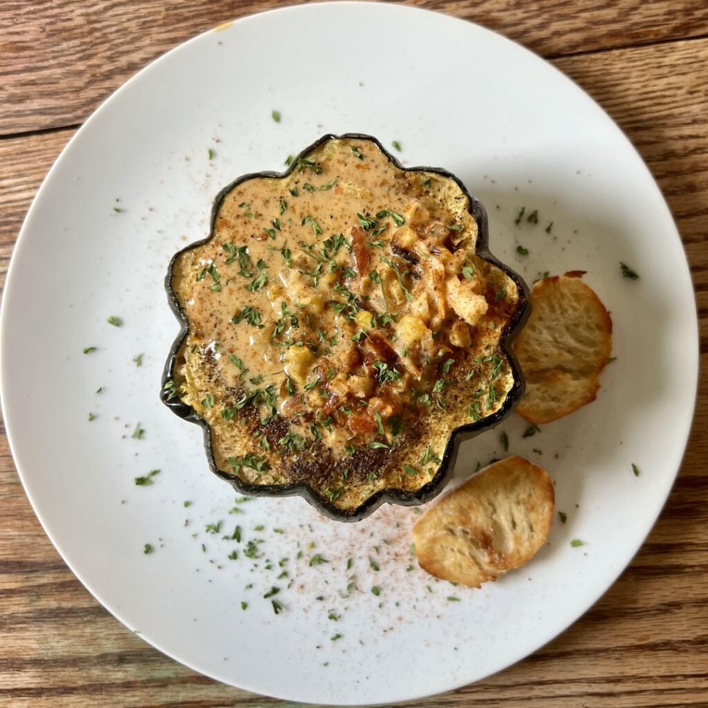 Acorn squash bowl filled with a lobster, pepper, and corn soup.
