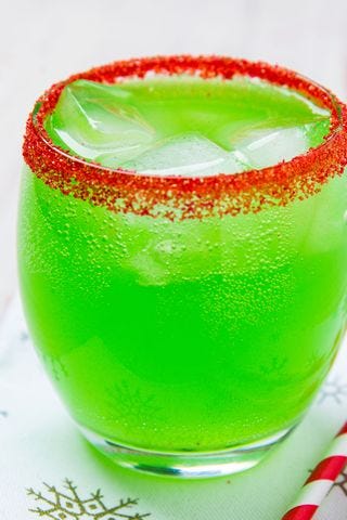 a glass of bright green punch with a red sugared rim
