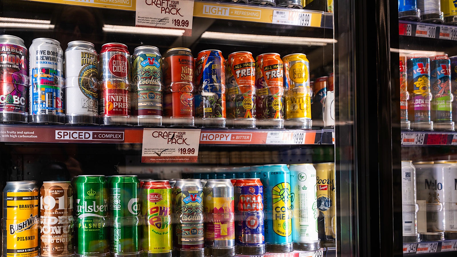 Dozens of colorful beer cans on a store shelf.