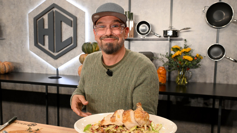 Michael Symon holding a plate of chicken at a cooking event