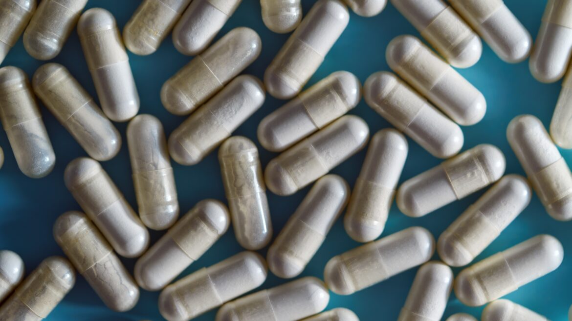 many supplement capsules scattered on a blue background