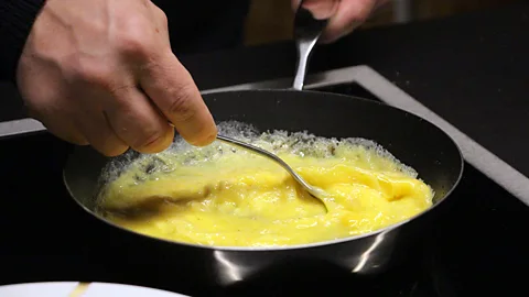 Emily Monaco Yves Camdeborde stirs the eggs gently, until they just begin to set (Credit: Emily Monaco)