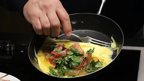 Emily Monaco After adding charcuterie and coriander, the omelette is rolled (Credit: Emily Monaco)