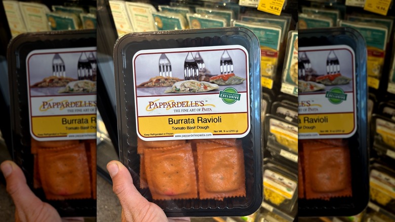 Hand holding a black container of red ravioli