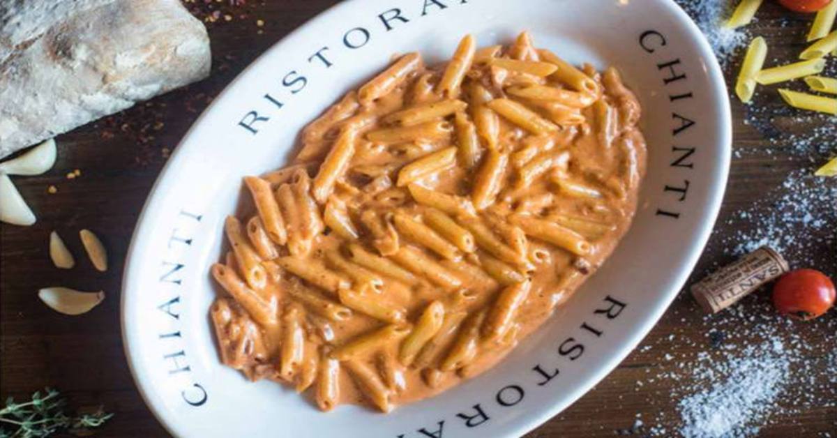 a white dish with pasta and creamy tomato sauce
