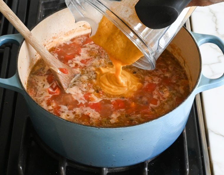 adding the bean and vegetable purée to the soup pot.