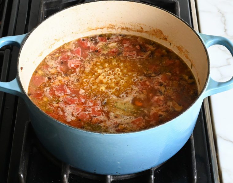 adding the pasta to the simmering broth.