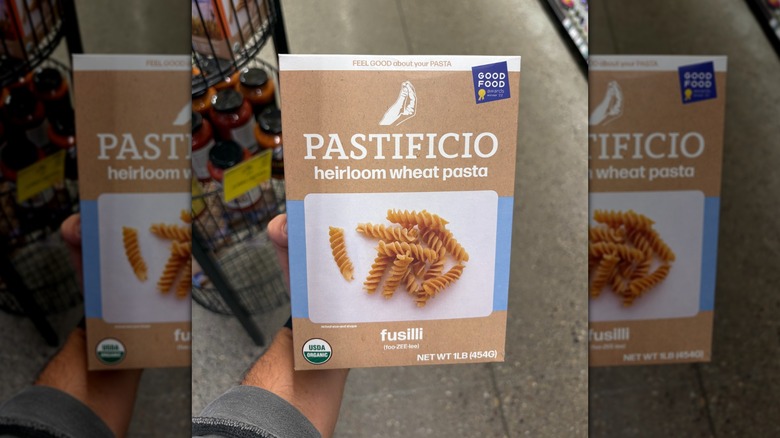 Hand holding a brown box of fusilli pasta