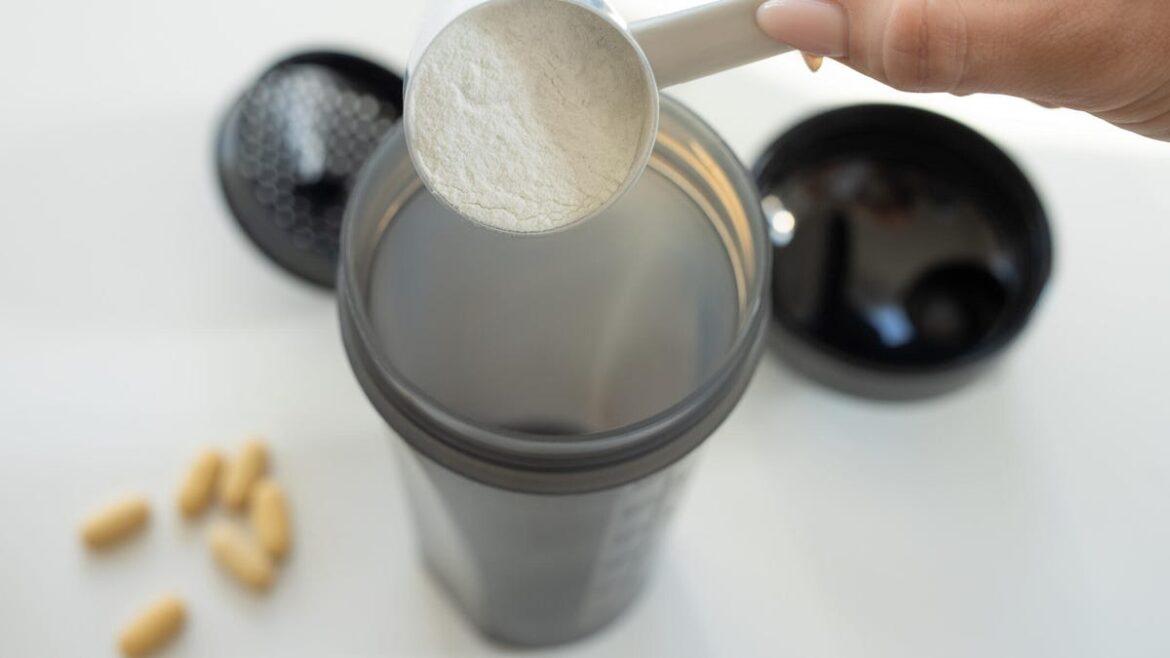 The Best Types of Creatine for All Your Fitness Goals, According to Experts A hand pouring a scoop of creatine powder into a blender container.