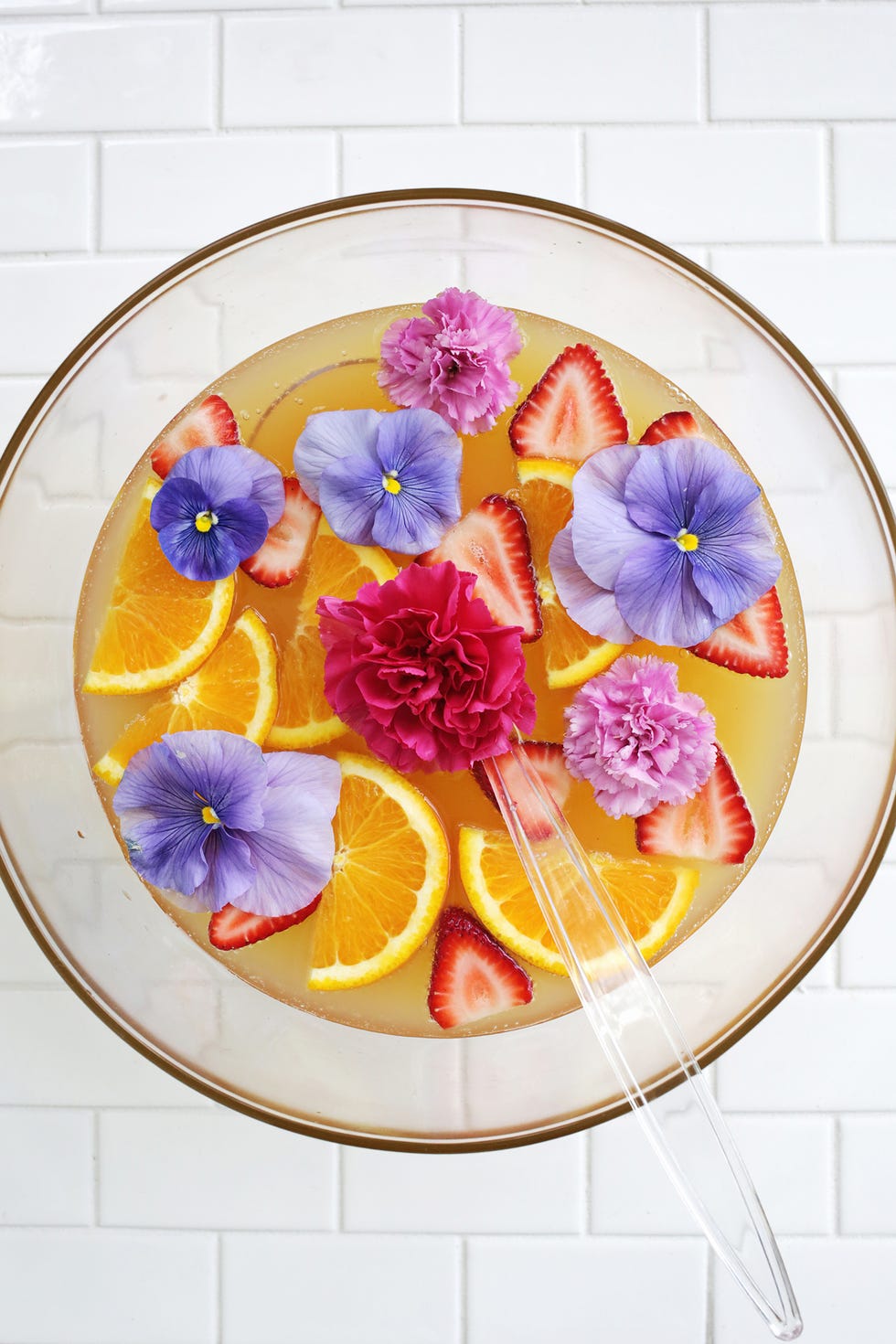 pineapple citrus punch with purple flowers, strawberries and orange slices