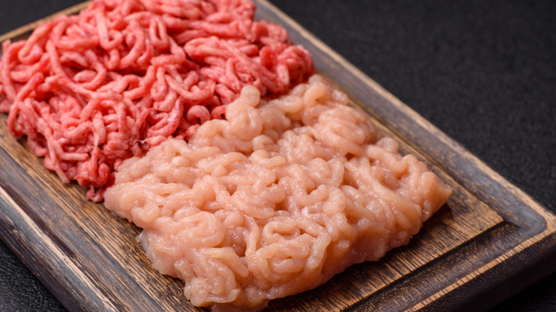Raw ground beef and poultry on wooden cutting board