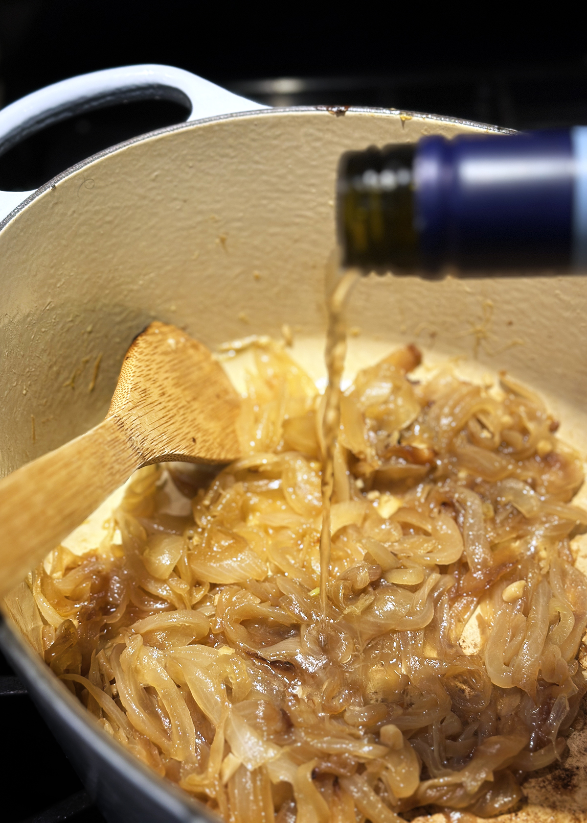 pouring wine from bottle into onion soup pot