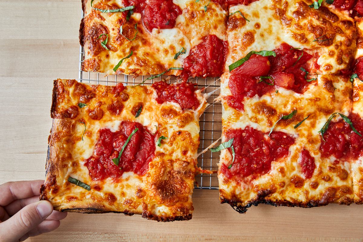 A square slice of pizza being pulled off from the corner.