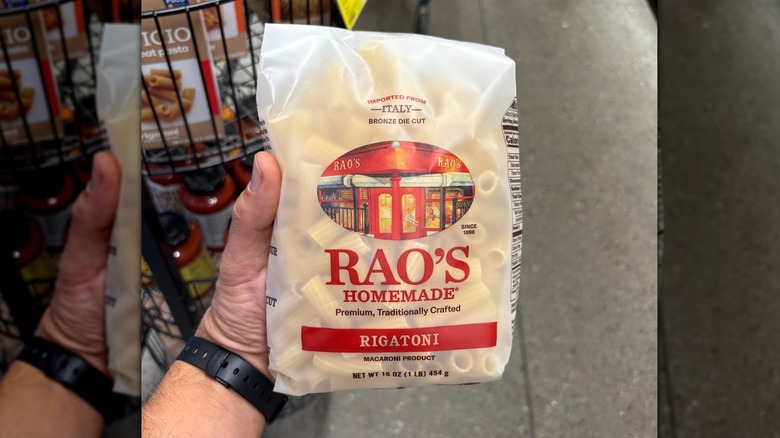 Hand holding a translucent bag of rigatoni pasta