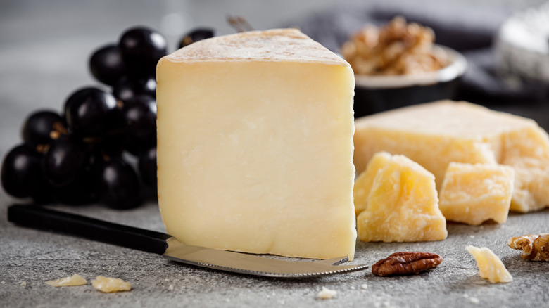Wedge of Pecorino Romano cheese next to black grapes and walnuts
