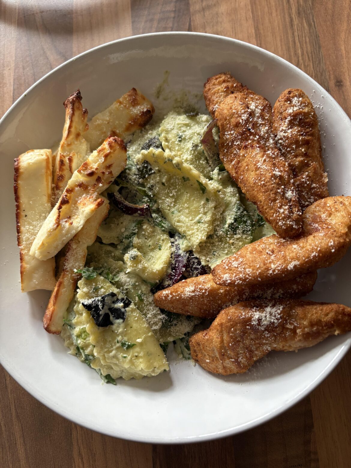 Filled pasta in a creamy pesto sauce, halloumi, & chicken goujons