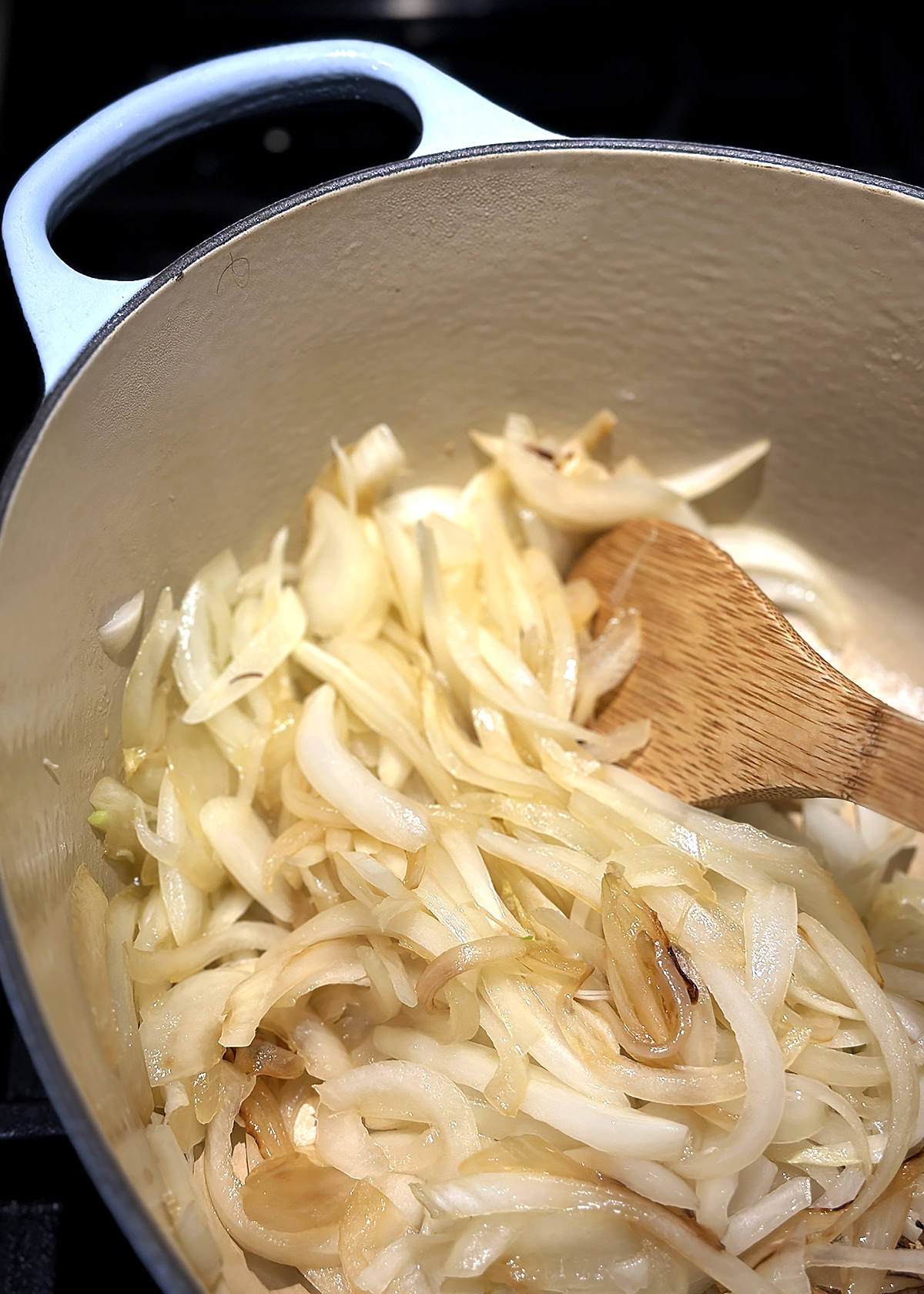 sliced white onions in pot, browning