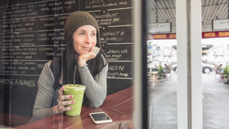 women drinks green smoothie at juice bar
