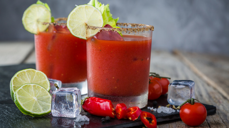 Tomato cocktails with lime slices, ice cubes, and sliced hot peppers