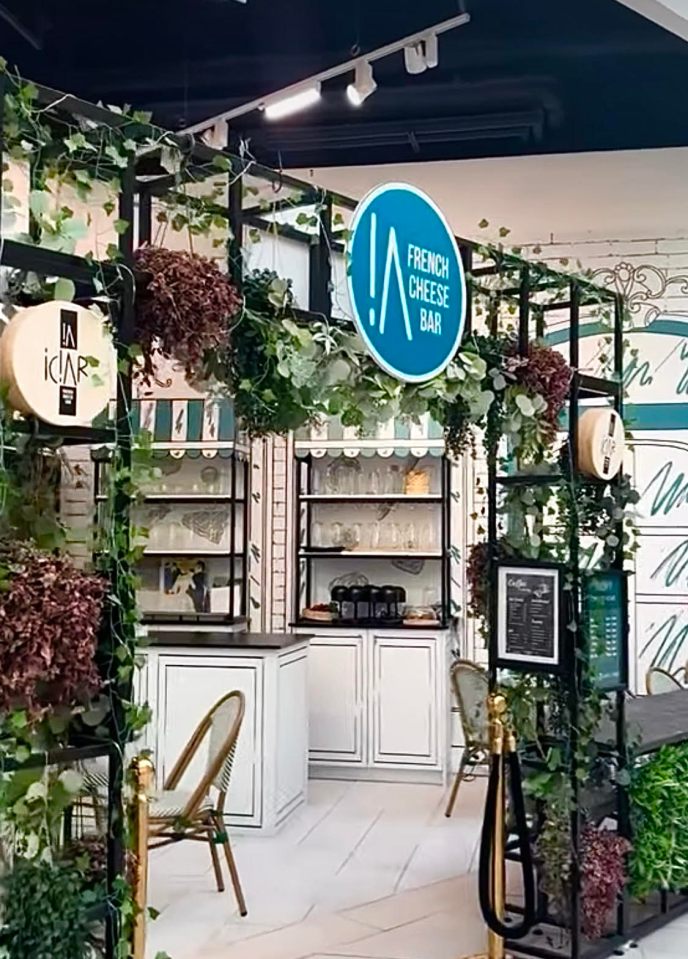 French cheese bar kiosk with greenery.