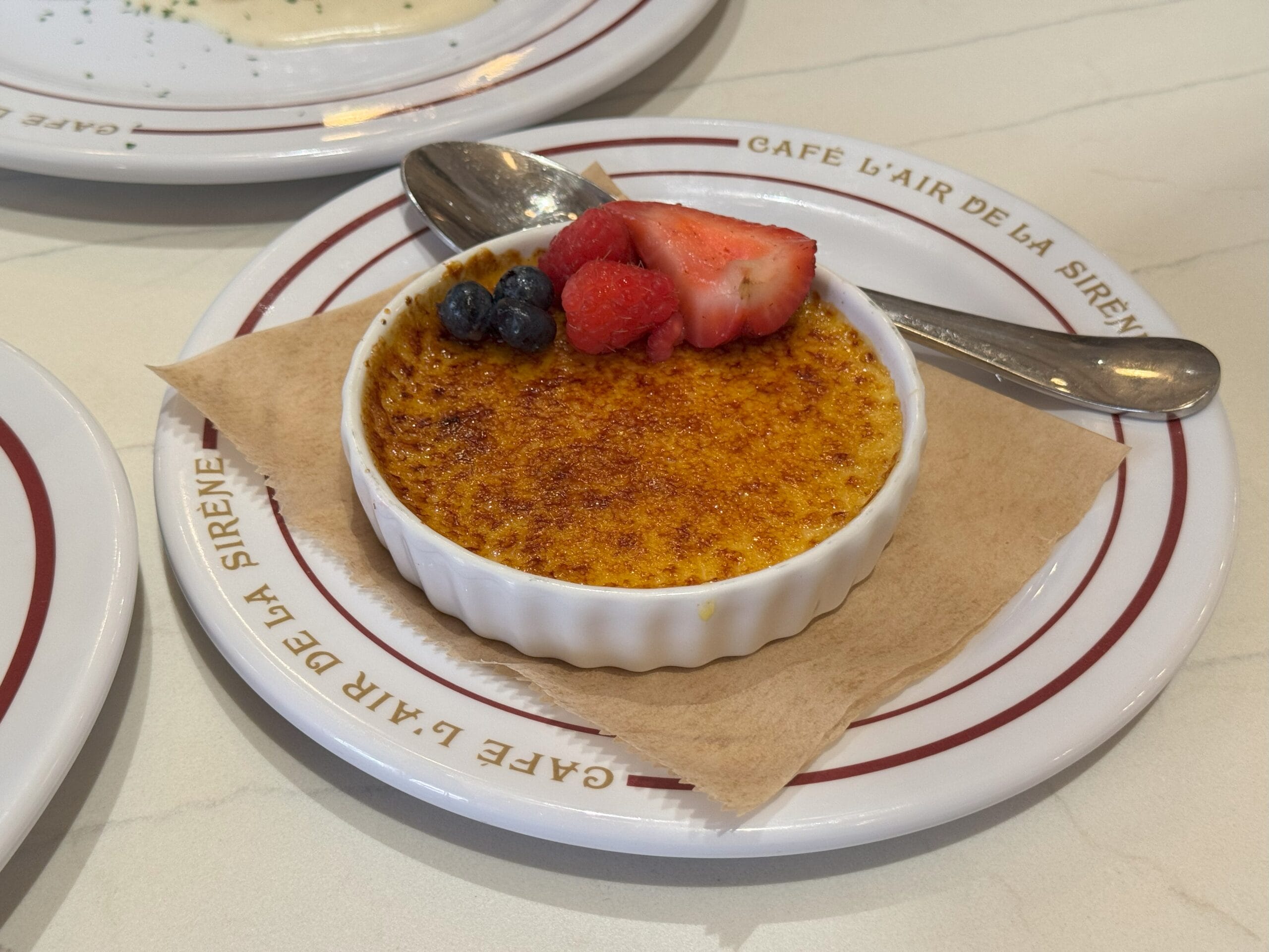 Crème brûlée topped with berries and a spoon, served at Cafe L’air de la Sirène in Epic Universe.