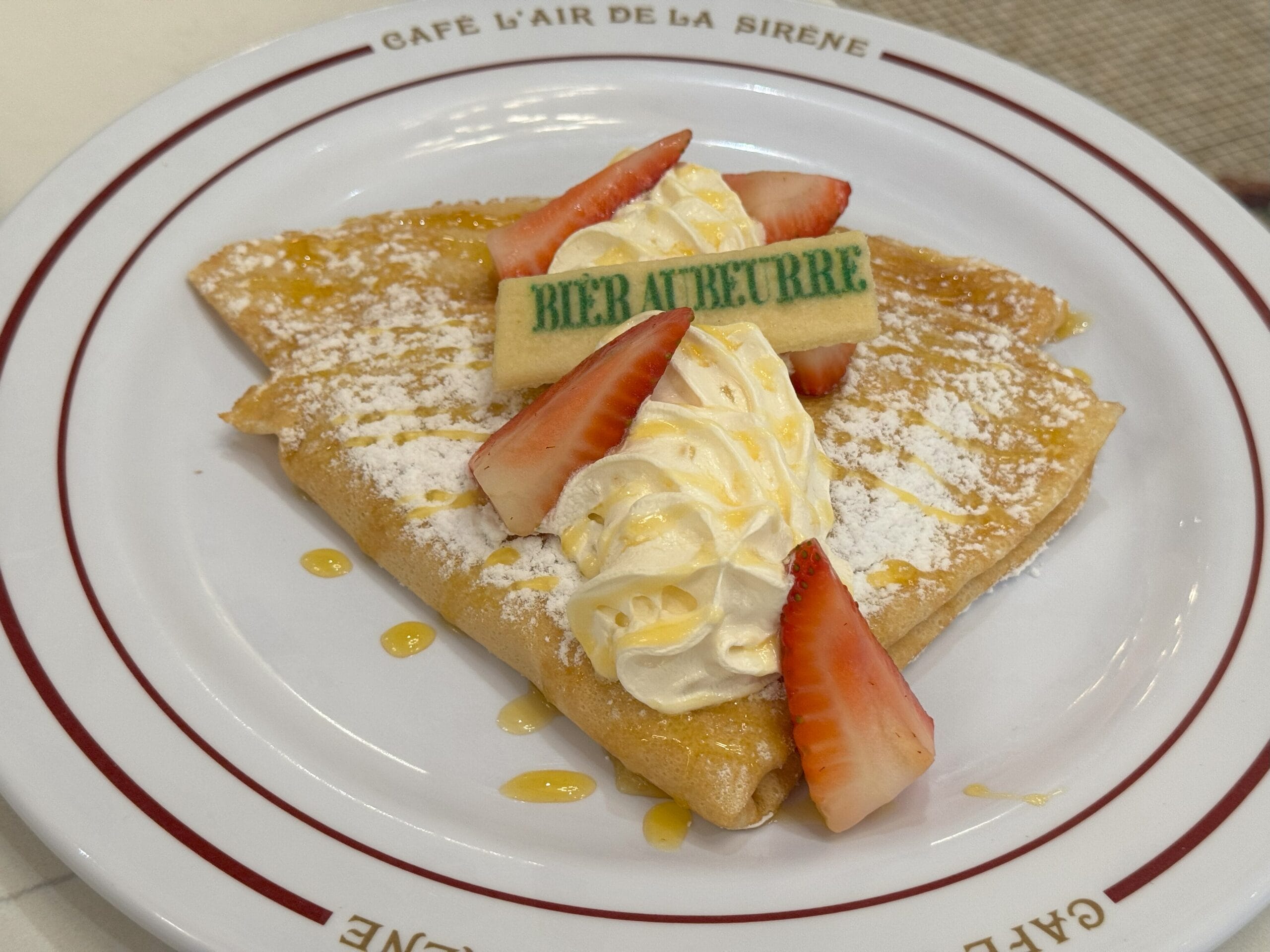 A folded crepe from Cafe L’air de la Sirène topped with whipped cream, strawberries, and a cookie—an Epic Universe treat!