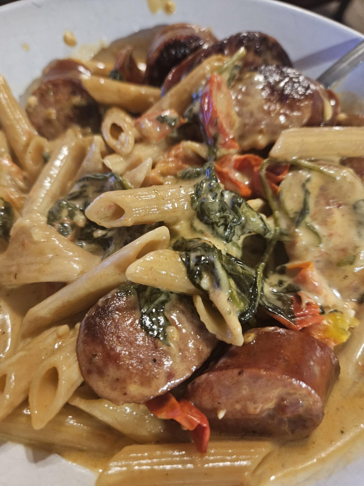 Andouille, whole wheat penne, cherry tomatoes from my garden, spinach, heavy whipping cream, fresh garlic, and shredded parmesan!