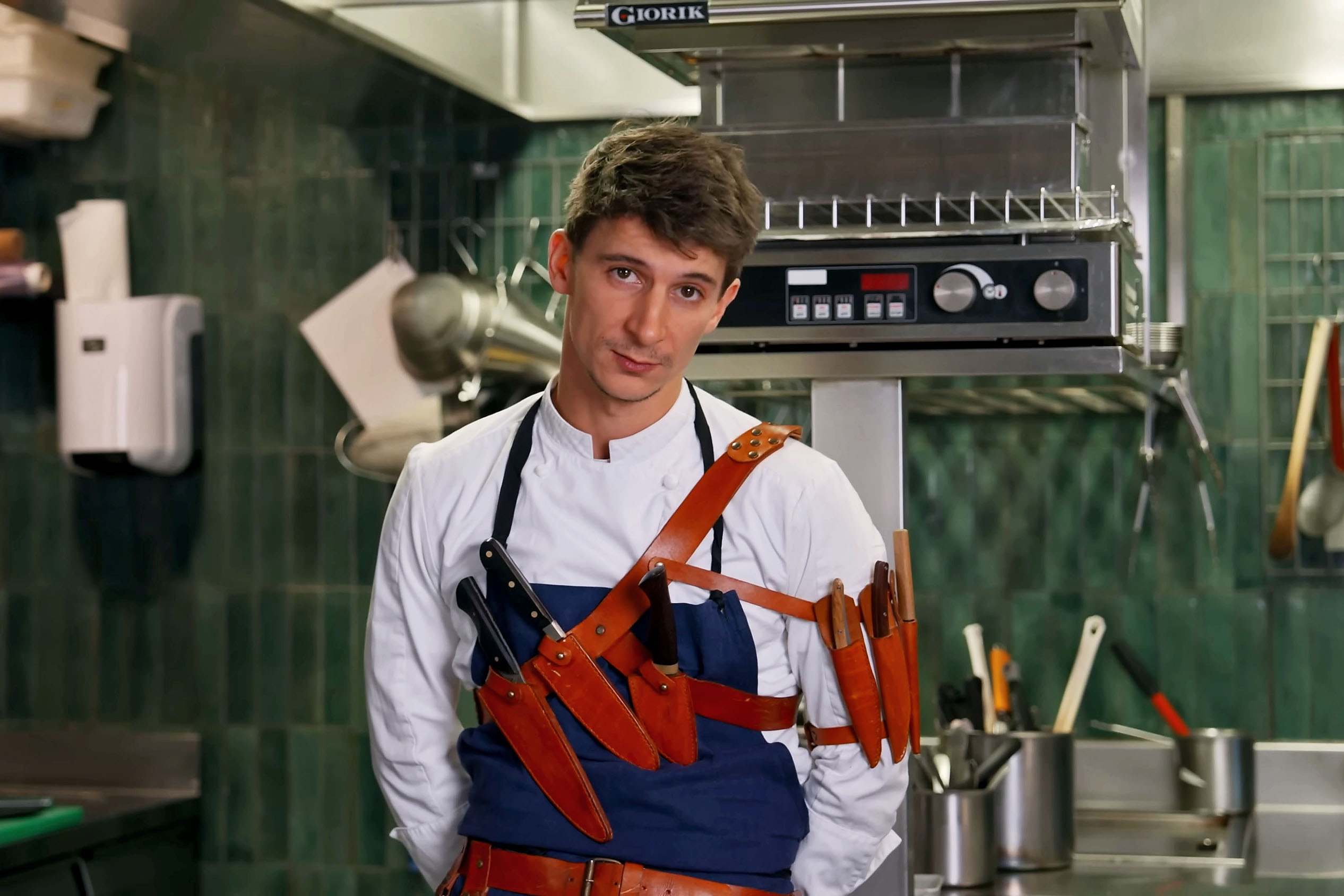 Eloy Spinnler, chef at Orgueil in Paris, wearing a chef's jacket and knife harness.