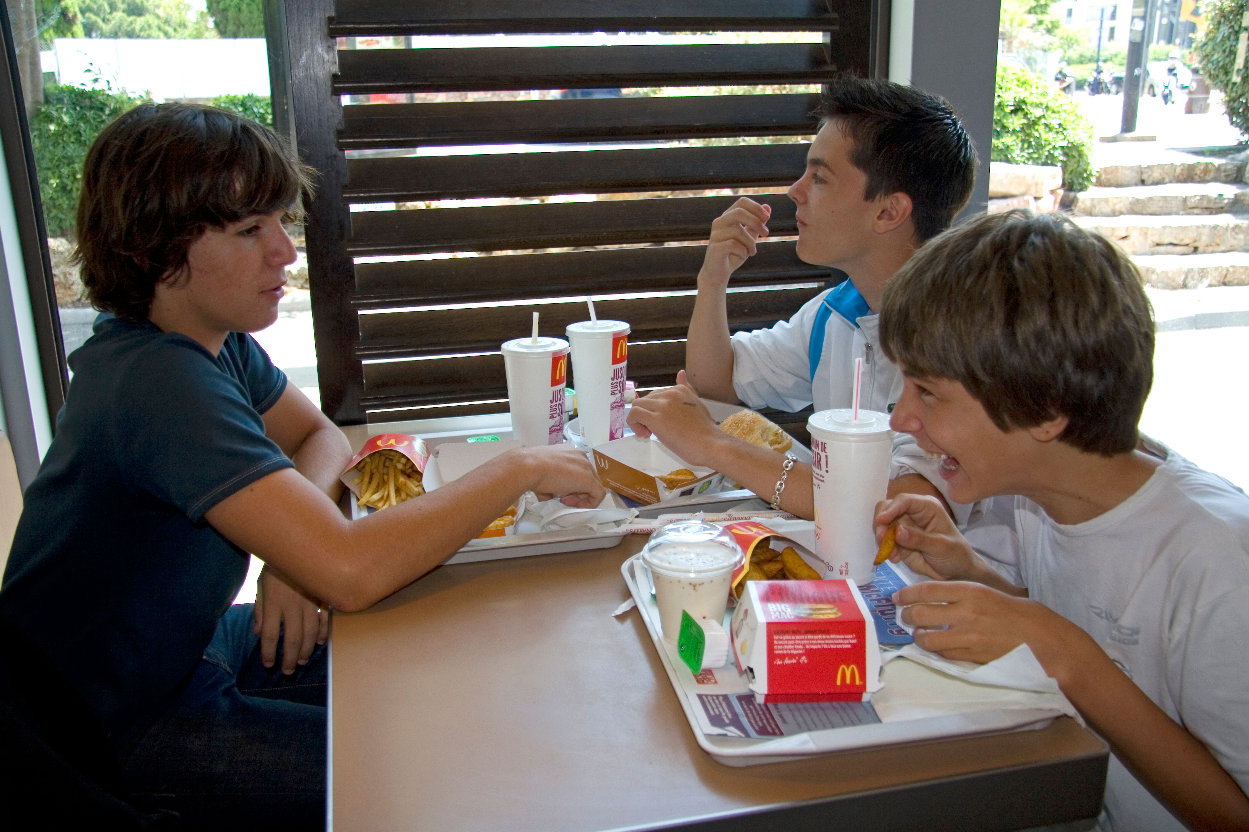 Three teenage boys eating at a McDonald's restaurant.