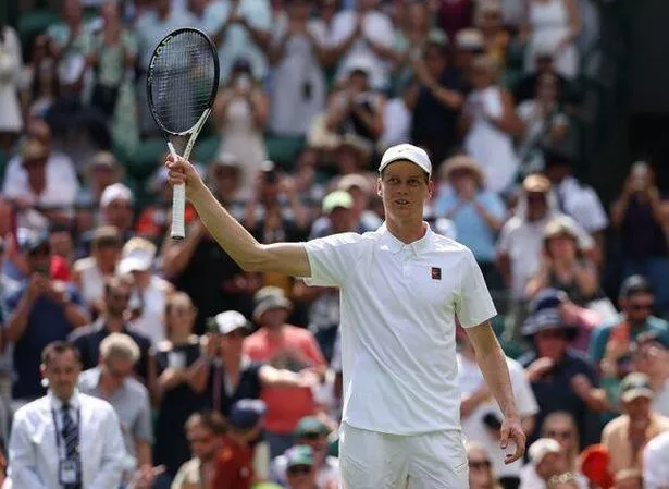 Jannik Sinner holds his tennis racket aloft