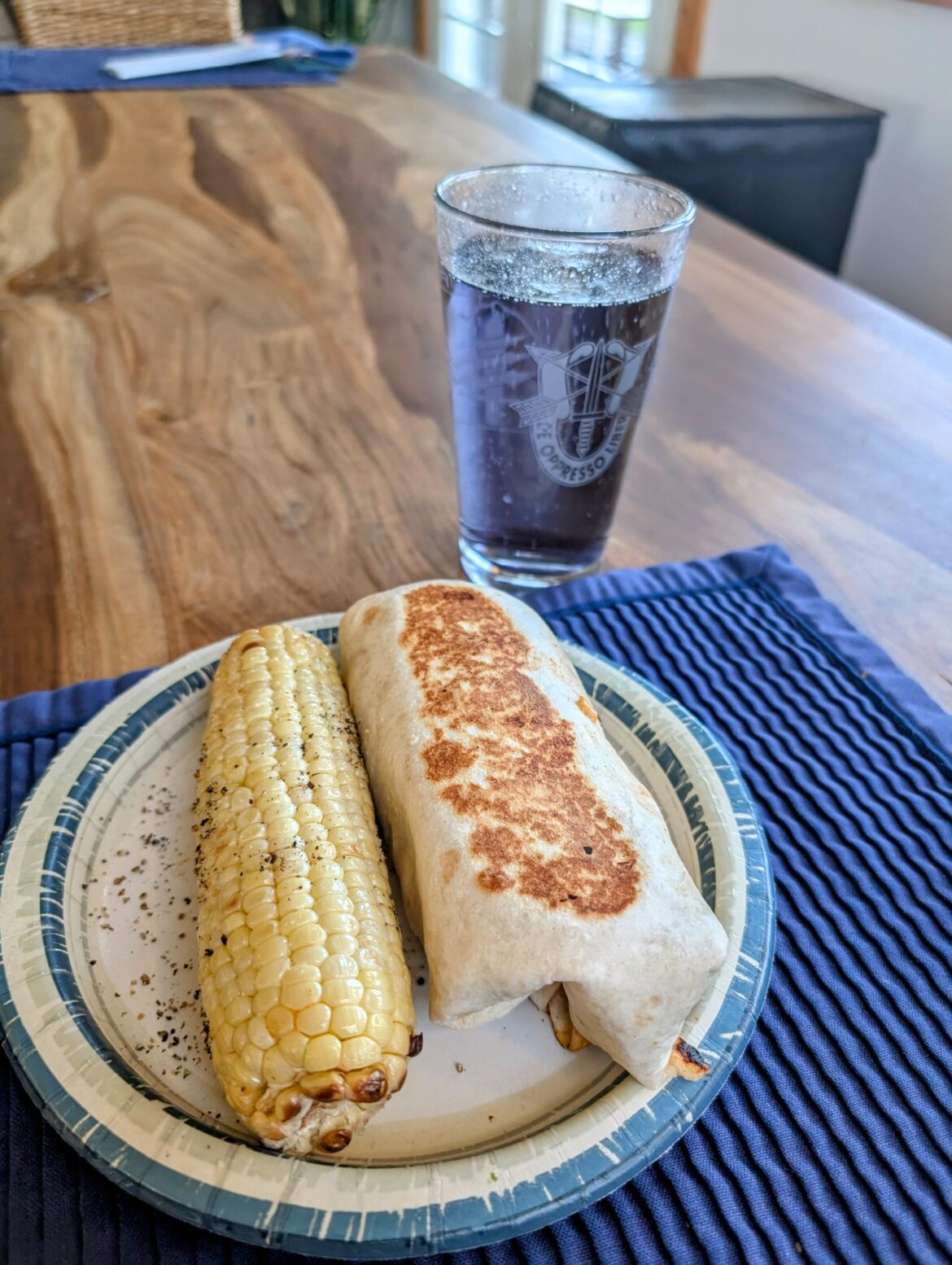 Chicken burrito, corn on the cob, and a glass of purple