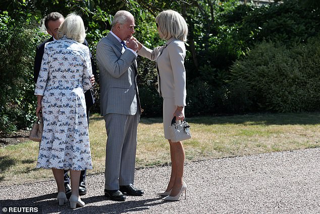 The King is seen kissing Brigitte Macron's hand in the gardens of Windsor Castle on day two of the French President's State Visit to the UK