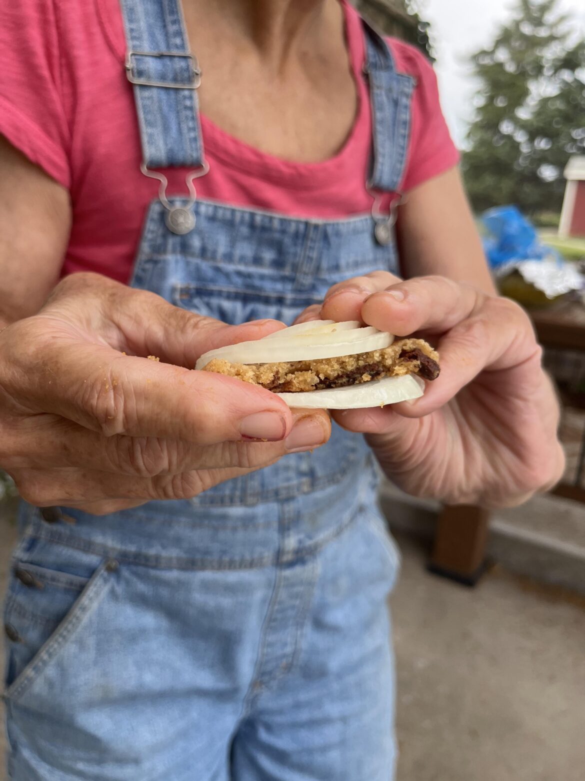 My mom eating a cookie between two slices of onion.