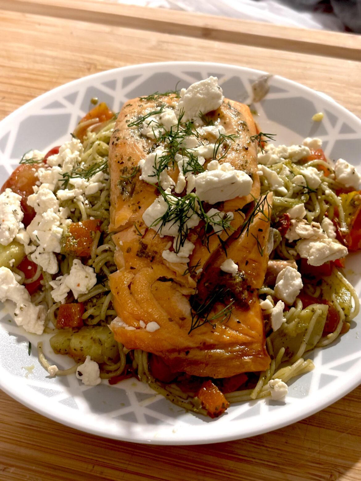 Lemon herb salmon with fresh dill and feta cheese, along with fresh pesto pasta and peppers, tomatoes and zucchini