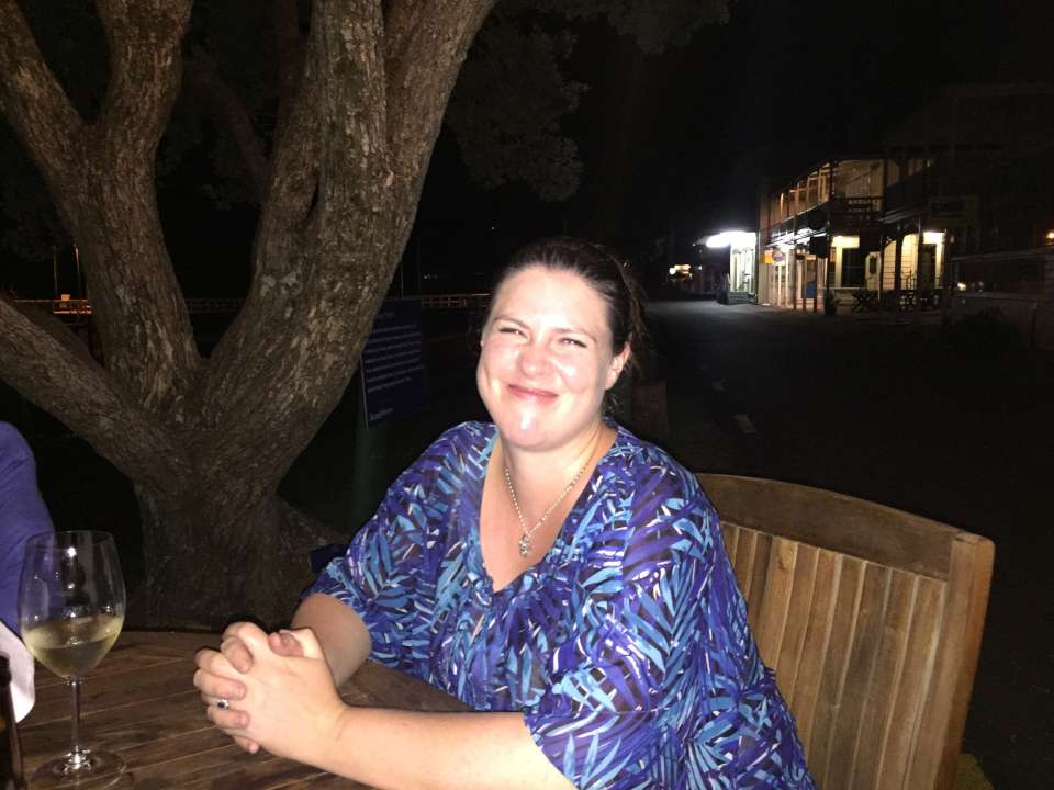Woman smiling at an outdoor restaurant at night.