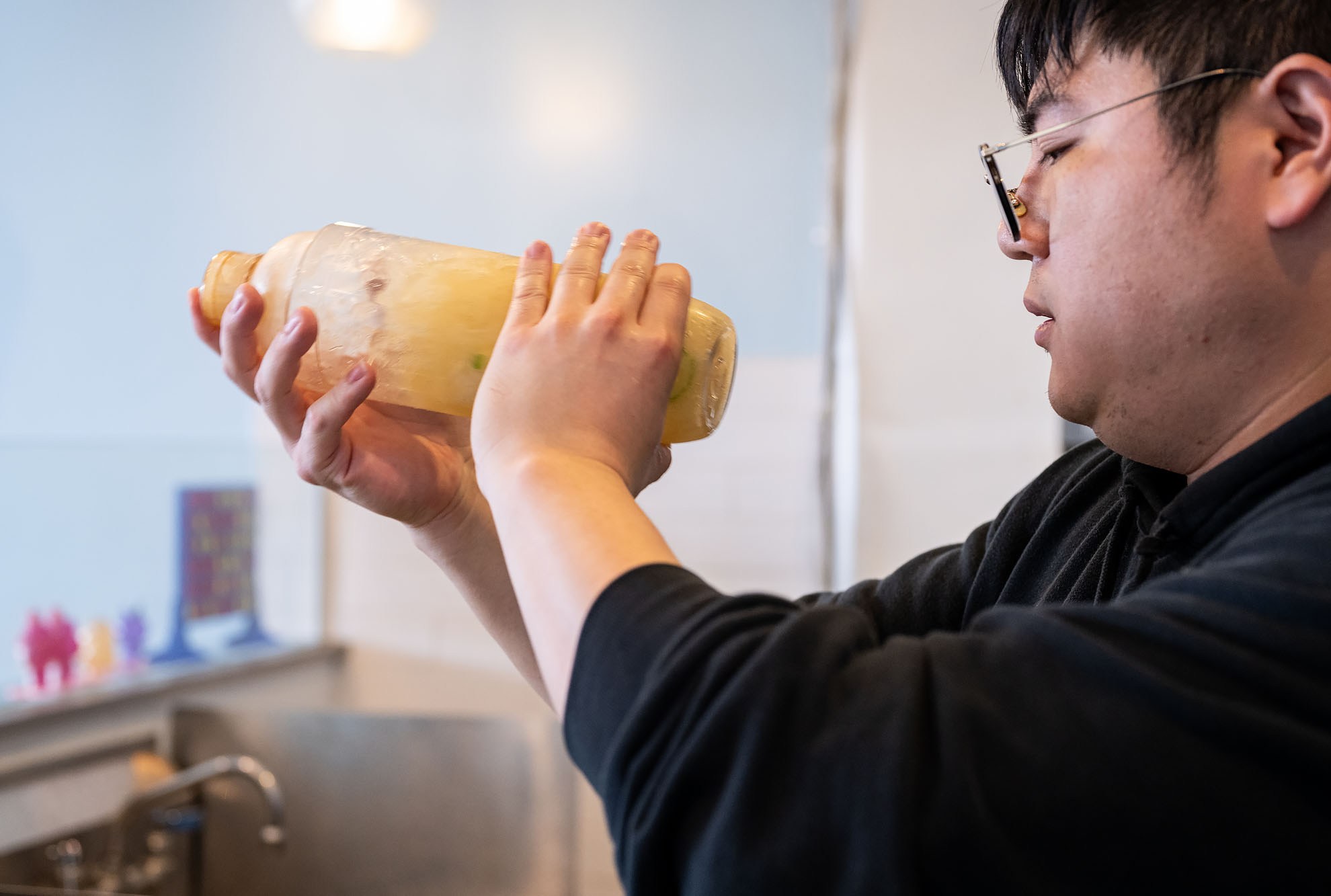 A man shakes up an iced lemon tea drink.