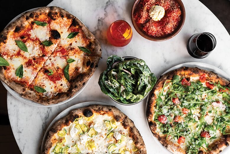 Assorted pizzas and dishes on a tabletop at Razza in Jersey City