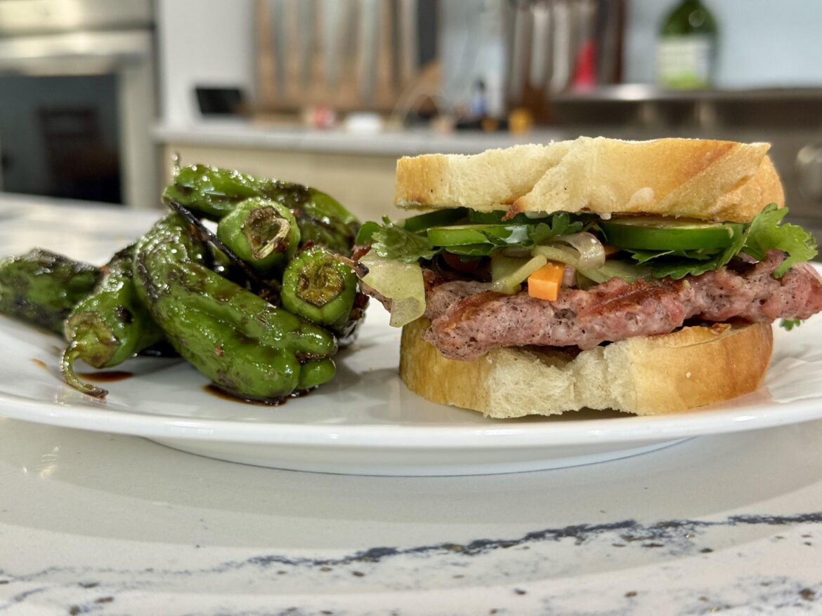 Banh mi pork burger on toasted french bread with blistered Sichuan shishitos