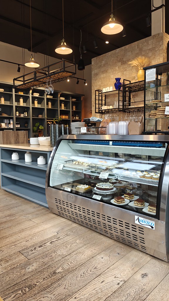 A shot of the display case holding the desserts and baked goods. You can also see wine glasses and stacks of dishes in the background, and in the very back is a huge bookshelf type wall.