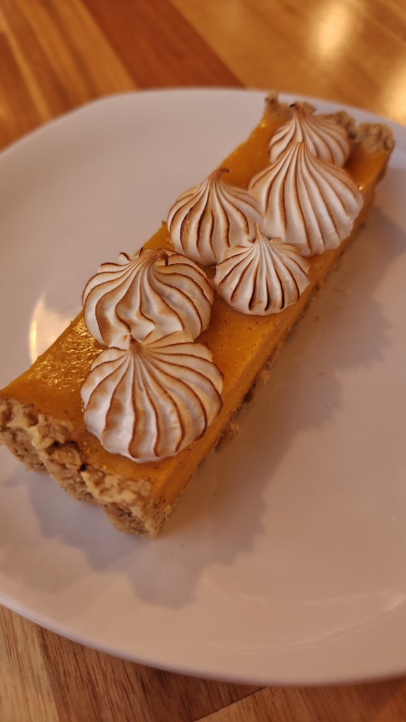 A long and narrow slice of a tart, the filling of which is bright orange and topped with dollops of toasted meringue (at least I think that's what it is?).