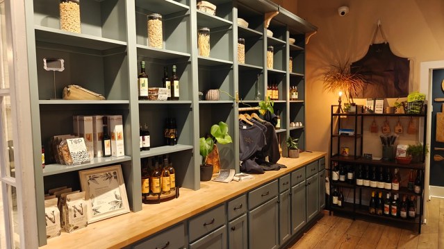 A huge bookshelf/cabinet set up that takes up an entire wall, and is painted a really pretty sea salt blue. The bookshelf looking portion is filled with jars of pasta, bottles of olive oils and some t-shirts for sale. There's also a really nice stand/shelving thingy on the other wall with wine bottles on it.