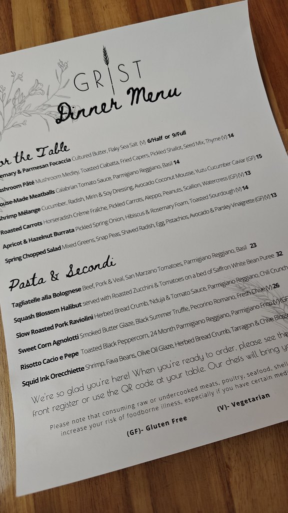 A paper menu, with two sections. One for starters and one for entrees. In the starters section there's rosemary and parmesan focaccia, mushroom pate, meatballs, shrimp melange, roasted carrots, apricot and hazelnut burrata, and spring chopped salad. For the entrees there's tagliatelle alla bolognese, squash blossom halibut, pork raviolini, sweet corn agnolotti, risotto cacio e pepe, and squid ink orecchiette.