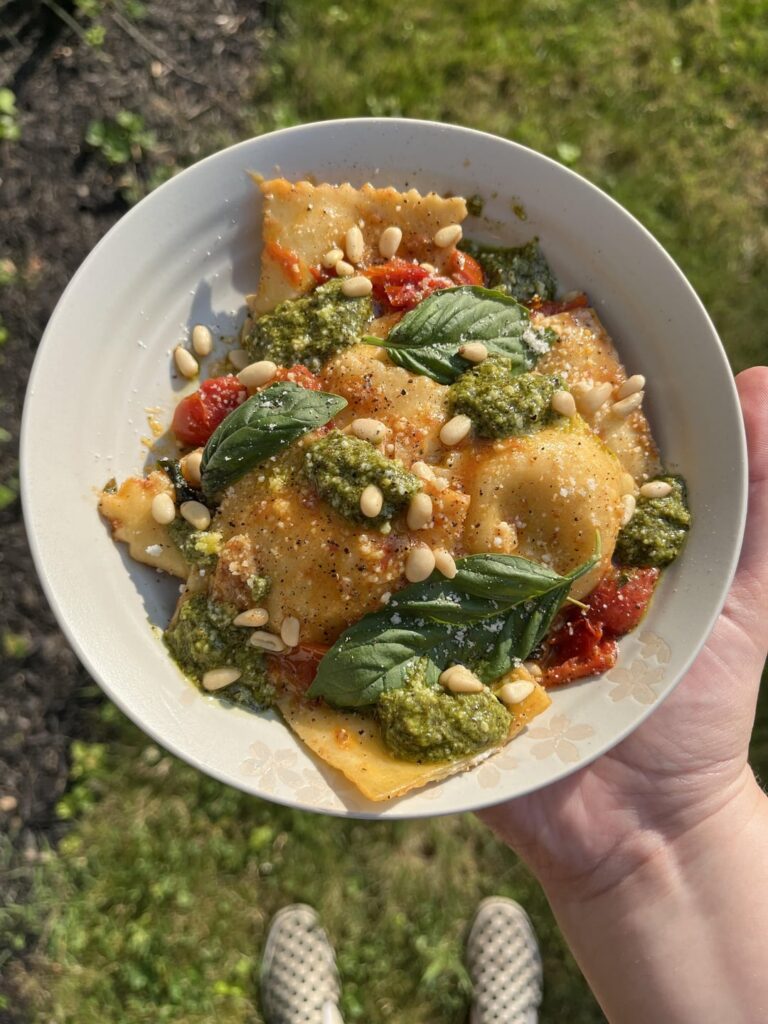 Homemade Ravioli stuffed with goat cheese, tomato + garlic sauce, pesto & pine nuts.