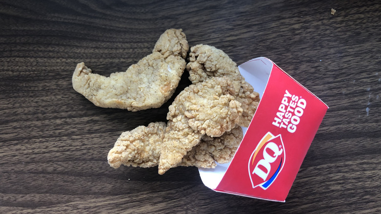 Order of four Dairy Queen chicken strips spilling out of the container onto a table
