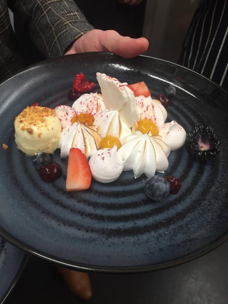 Trio of meringue Swiss french and Italian with a vanilla and coconut pana cotta coated in white chocolate with a  caramelised white chocolate passion fruit gel mixed berry gel and fresh berries